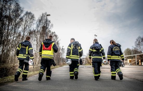 fem brandmän går med ryggen vända mot kameran