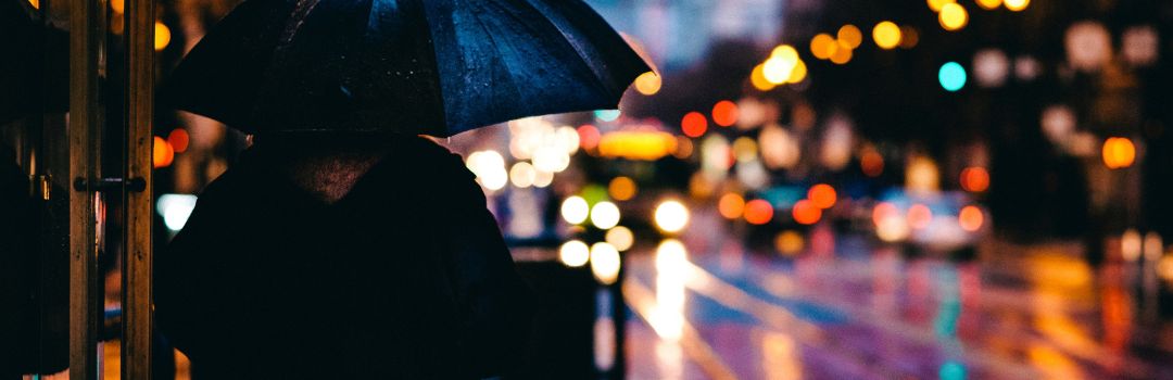 person som står med paraply i mörkret