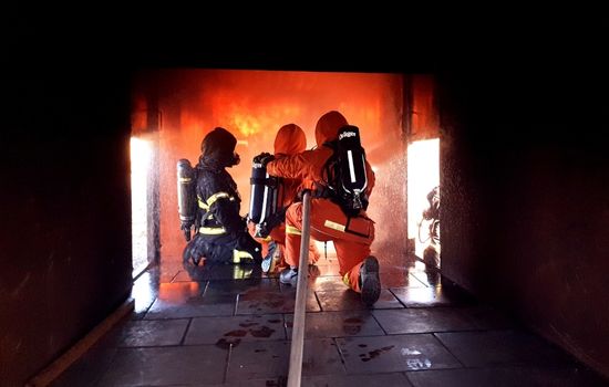 tre brandmän som släcker en eld i ett trångt utrymme